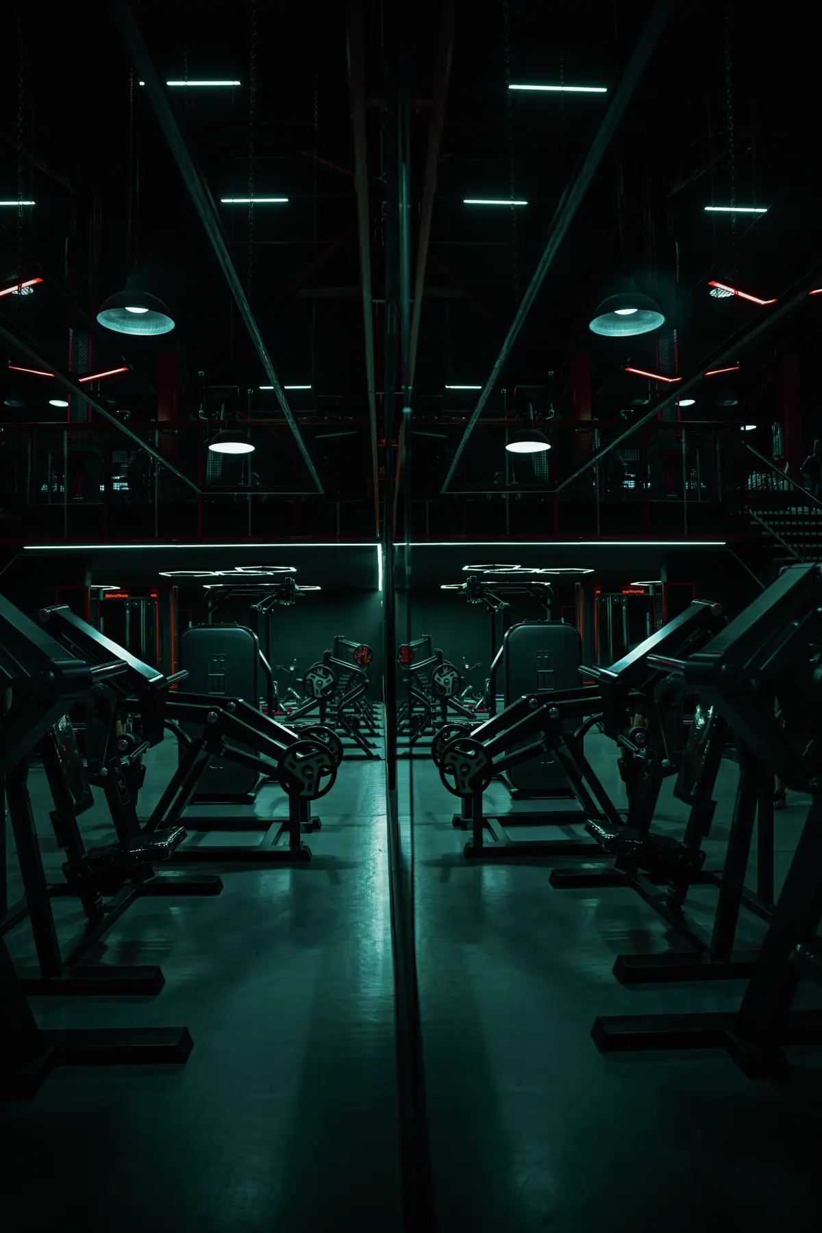 Fileira de máquinas de musculação refletidas em espelho sob luz baixa
