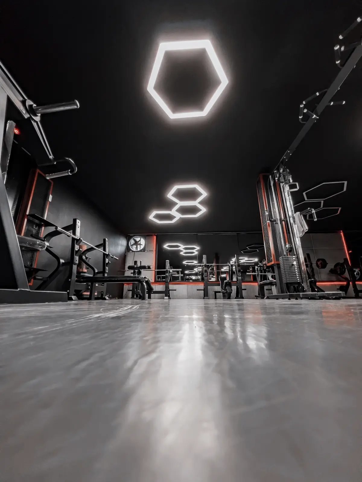 Salão de musculação com luminárias hexagonais no teto